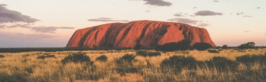 Hellrot leuchtender Uluru Ayers Rock Inselberg während Australien Reise in Wüste